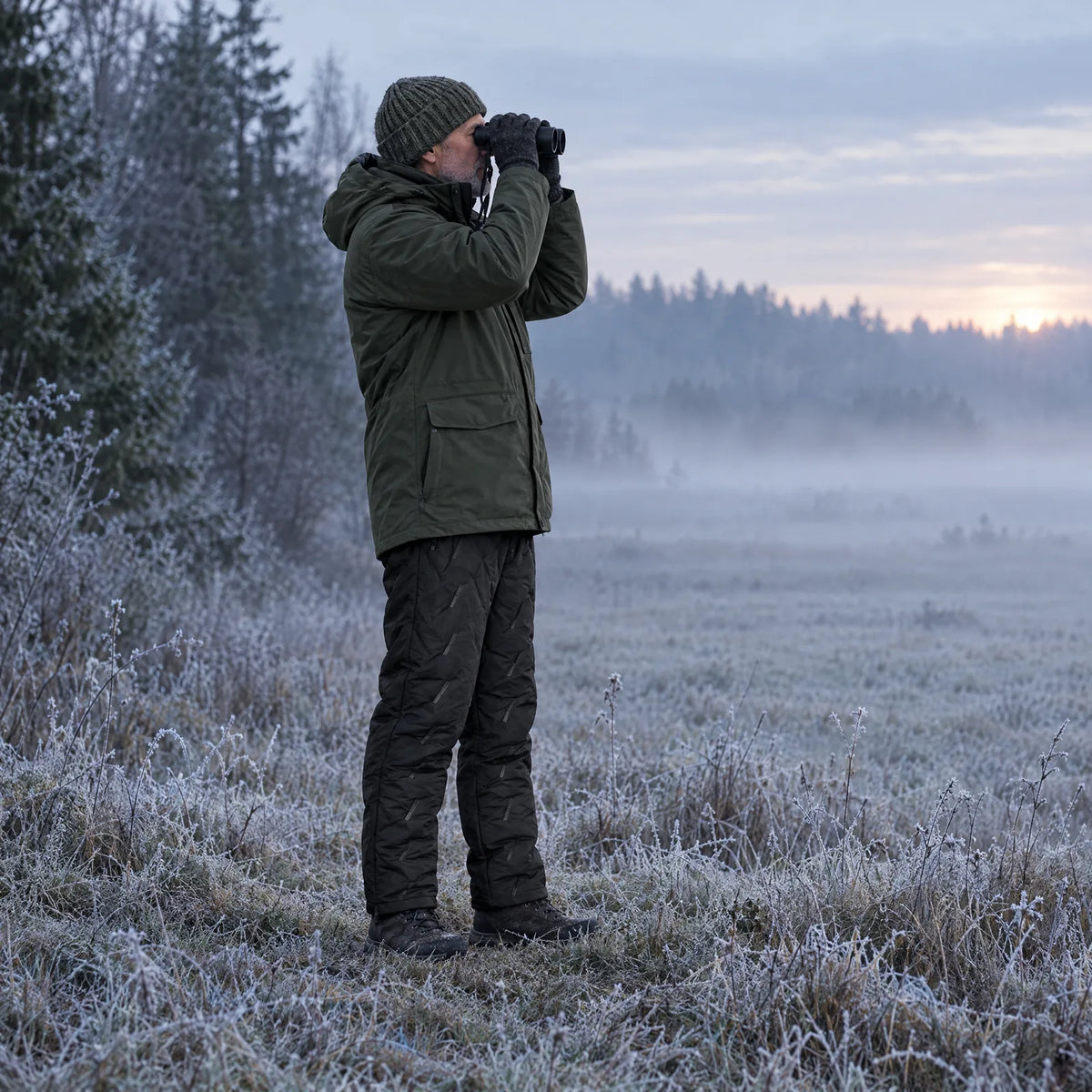 Vogelbeobachtung auf einer frostigen Wiese in der beheizten Winterhose